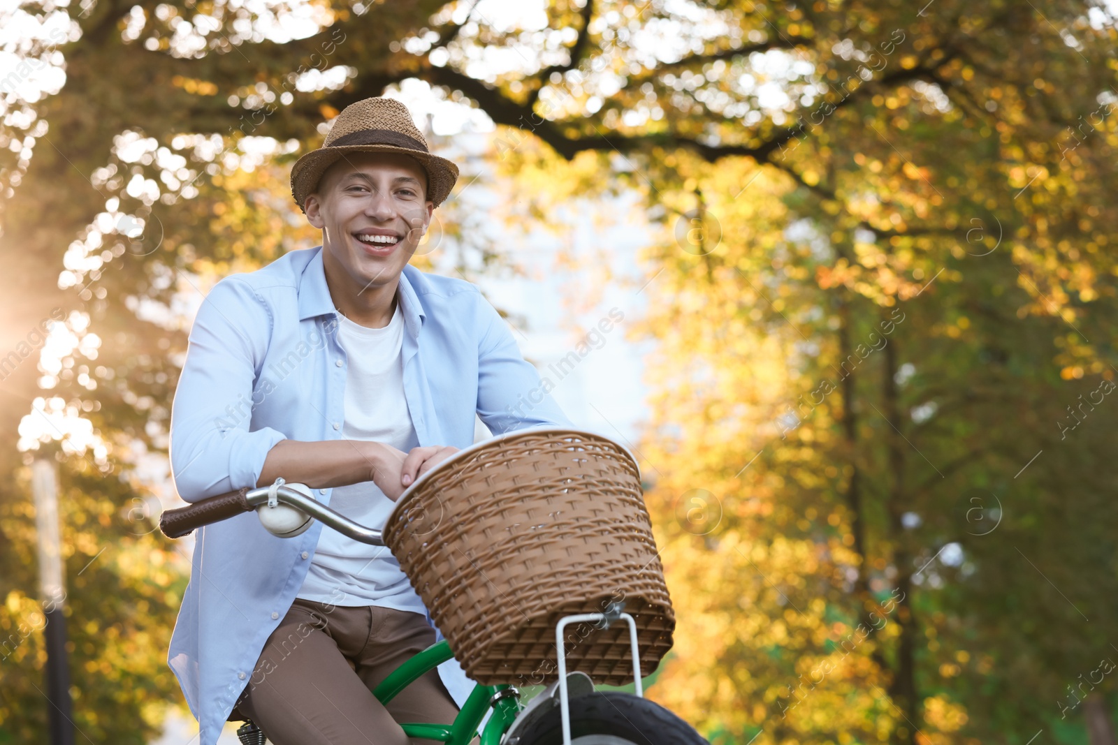Photo of Happy man riding bicycle in park on sunny day. Space for text