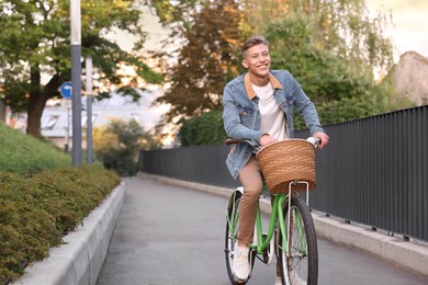 Photo of Happy man riding bicycle on city street. Space for text