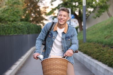 Photo of Happy man with backpack riding bicycle on city street