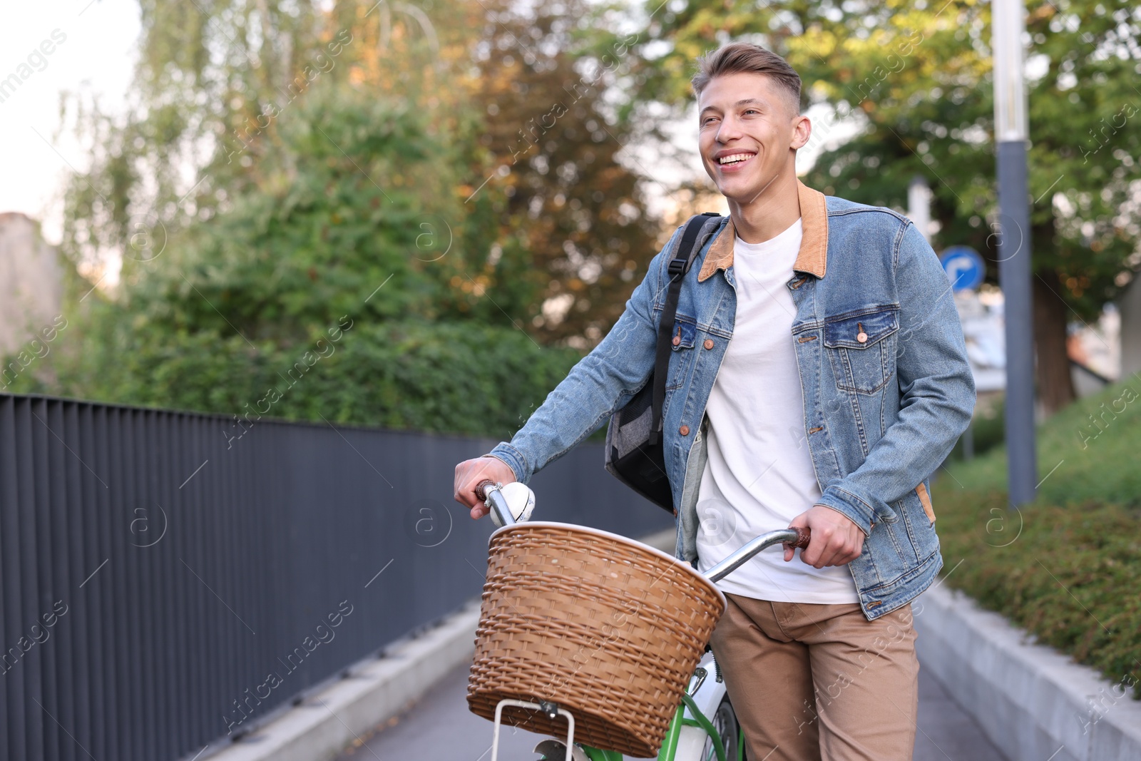 Photo of Happy man with backpack riding bicycle on city street. Space for text