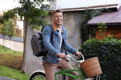 Photo of Happy man with backpack riding bicycle on city street