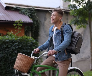 Photo of Happy man with backpack riding bicycle on city street