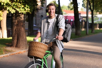 Photo of Happy man listening to music while riding bicycle in park