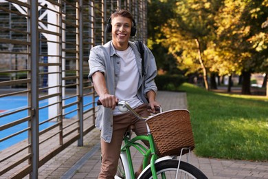 Photo of Happy man listening to music while riding bicycle in park