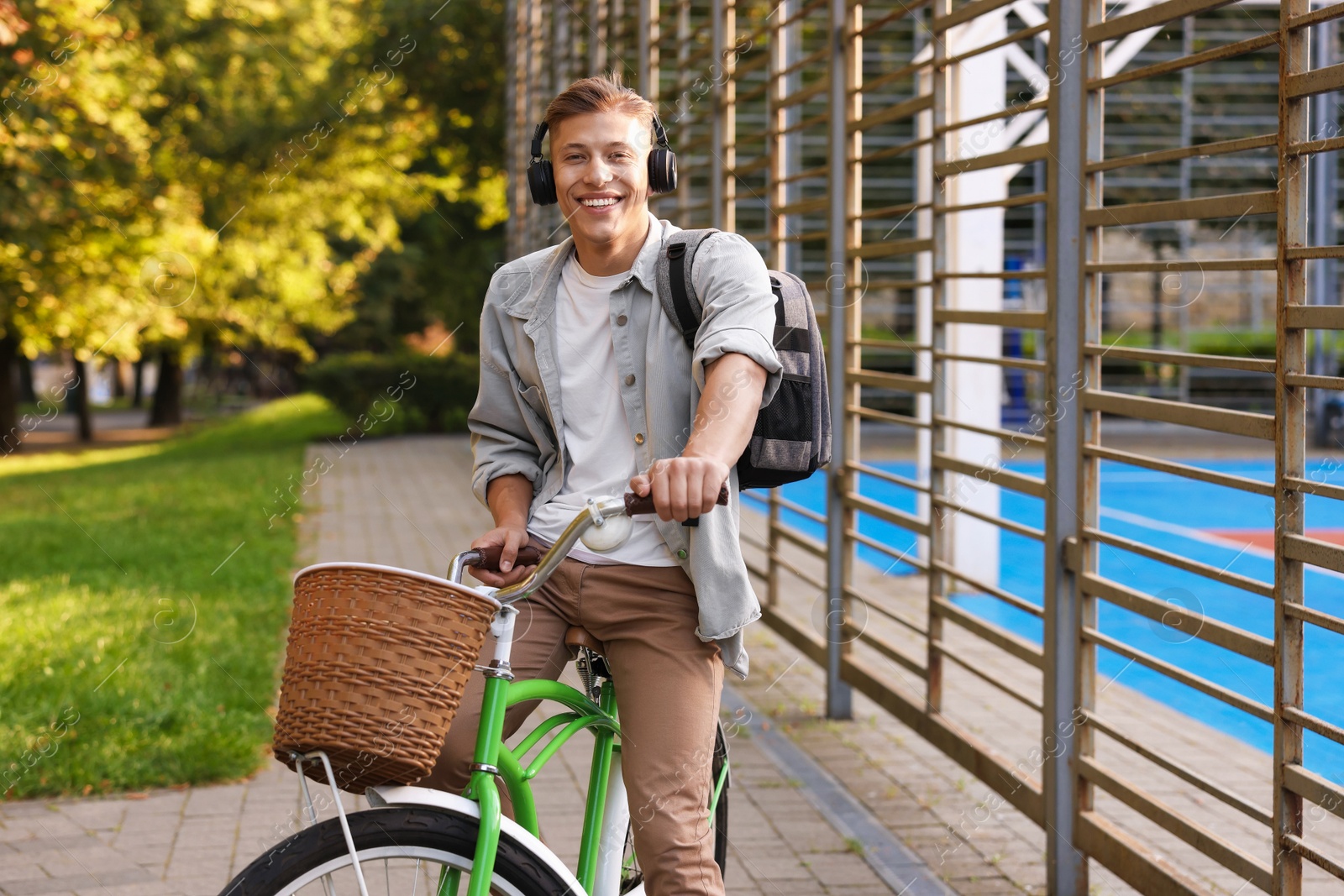 Photo of Happy man listening to music while riding bicycle in park