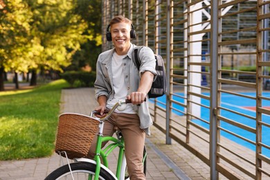 Photo of Happy man listening to music while riding bicycle in park