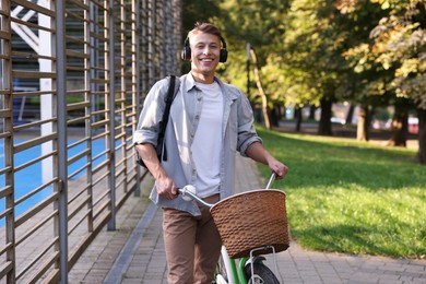 Photo of Happy man listening to music while riding bicycle in park