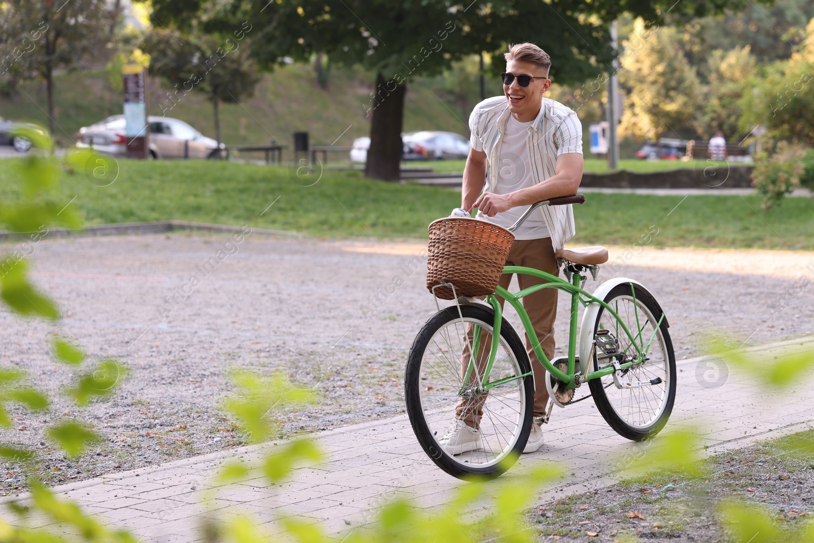 Photo of Happy man walking his bicycle on city street. Space for text