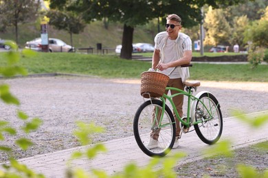 Photo of Happy man walking his bicycle on city street. Space for text