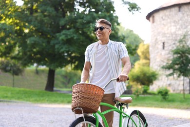 Photo of Happy man walking his bicycle on city street. Space for text