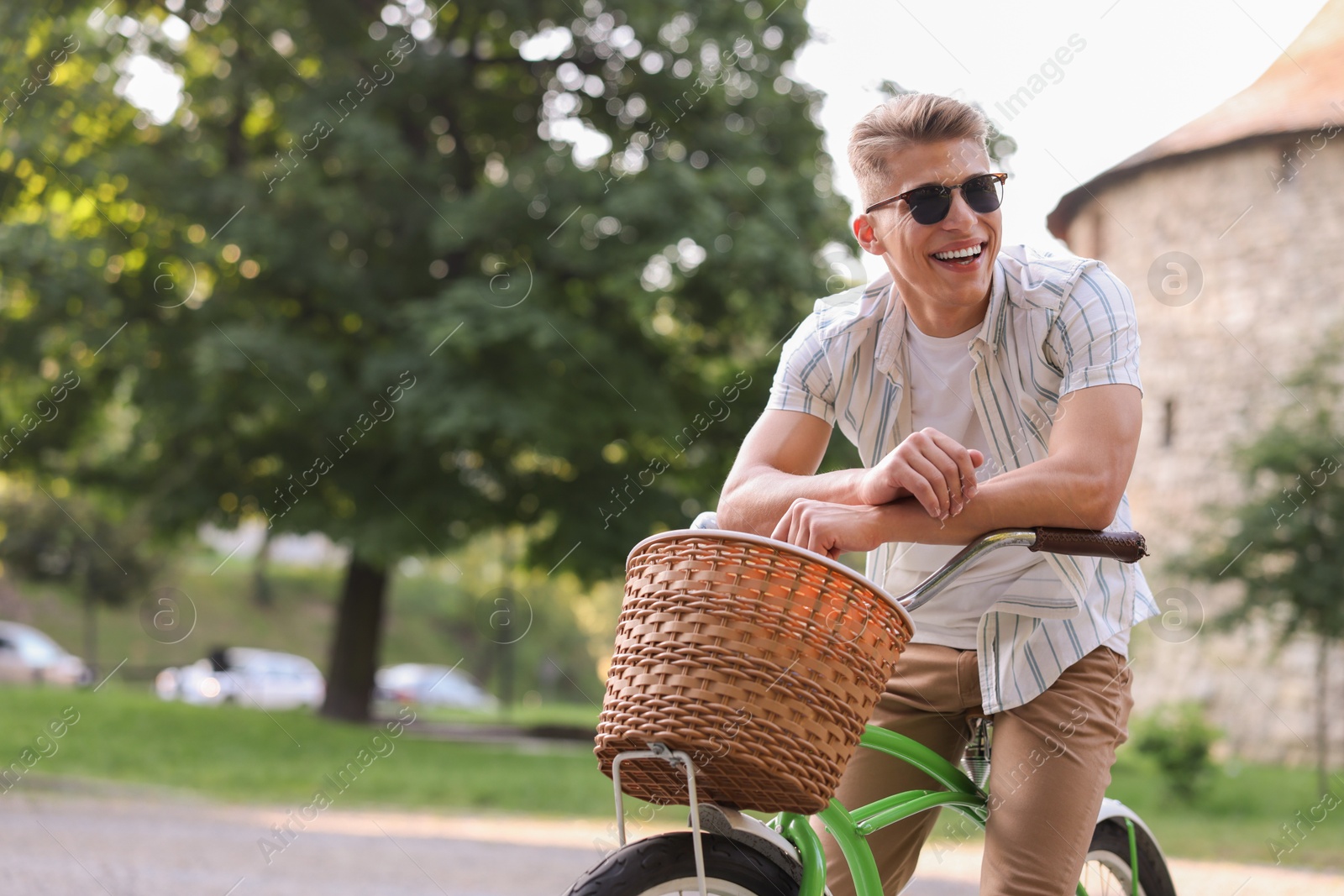 Photo of Happy man riding bicycle on city street. Space for text