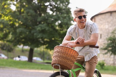 Photo of Happy man riding bicycle on city street. Space for text