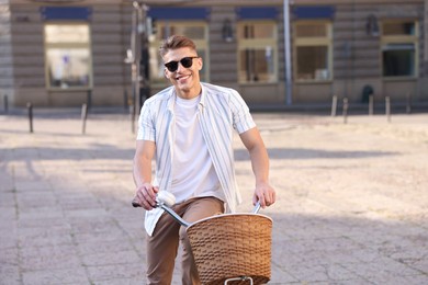 Photo of Happy man in sunglasses riding bicycle on city street