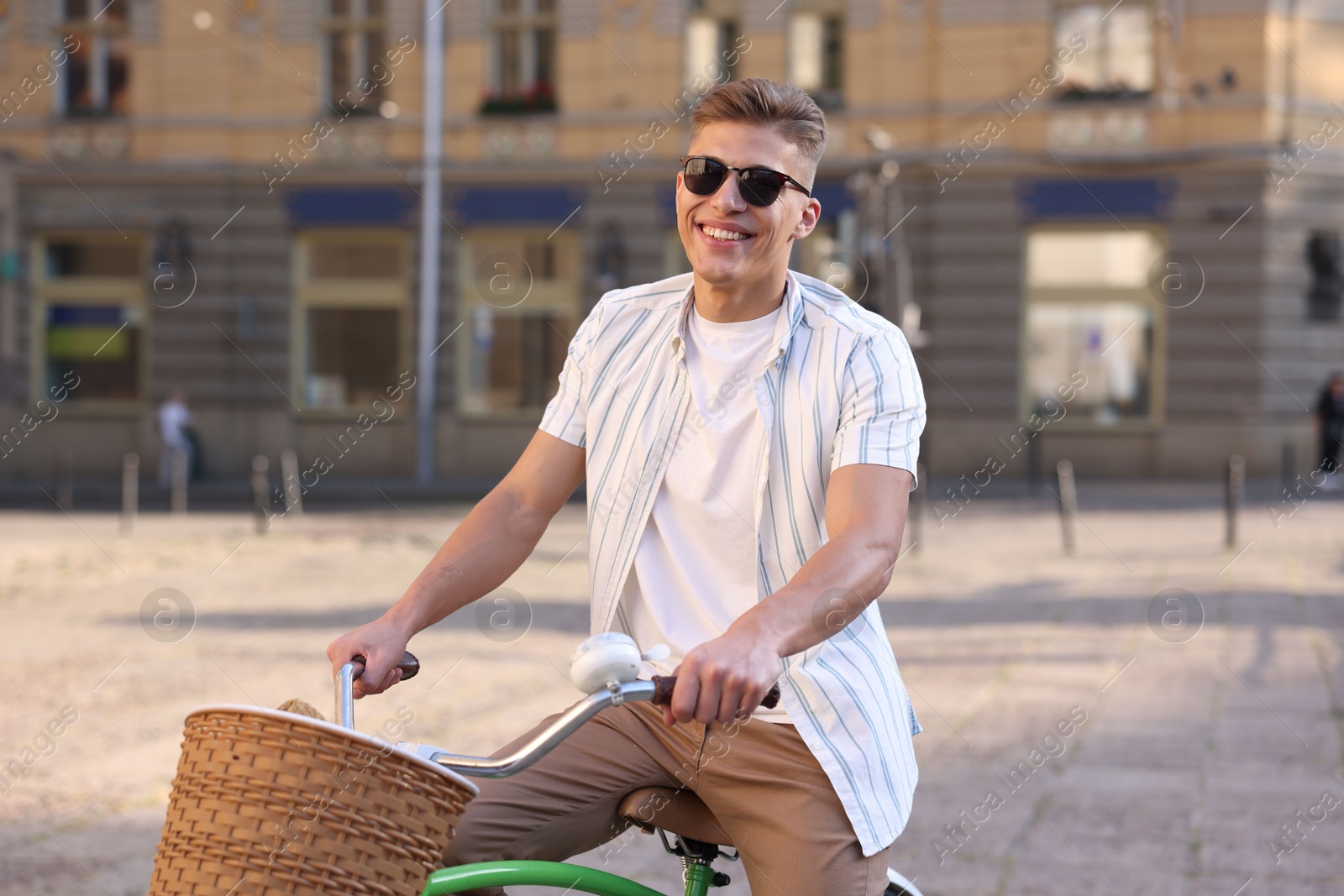 Photo of Happy man in sunglasses riding bicycle on city street