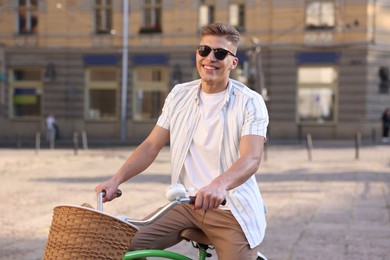 Photo of Happy man in sunglasses riding bicycle on city street