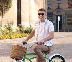 Photo of Happy man in sunglasses riding bicycle on city street