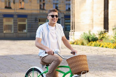 Photo of Happy man in sunglasses riding bicycle on city street