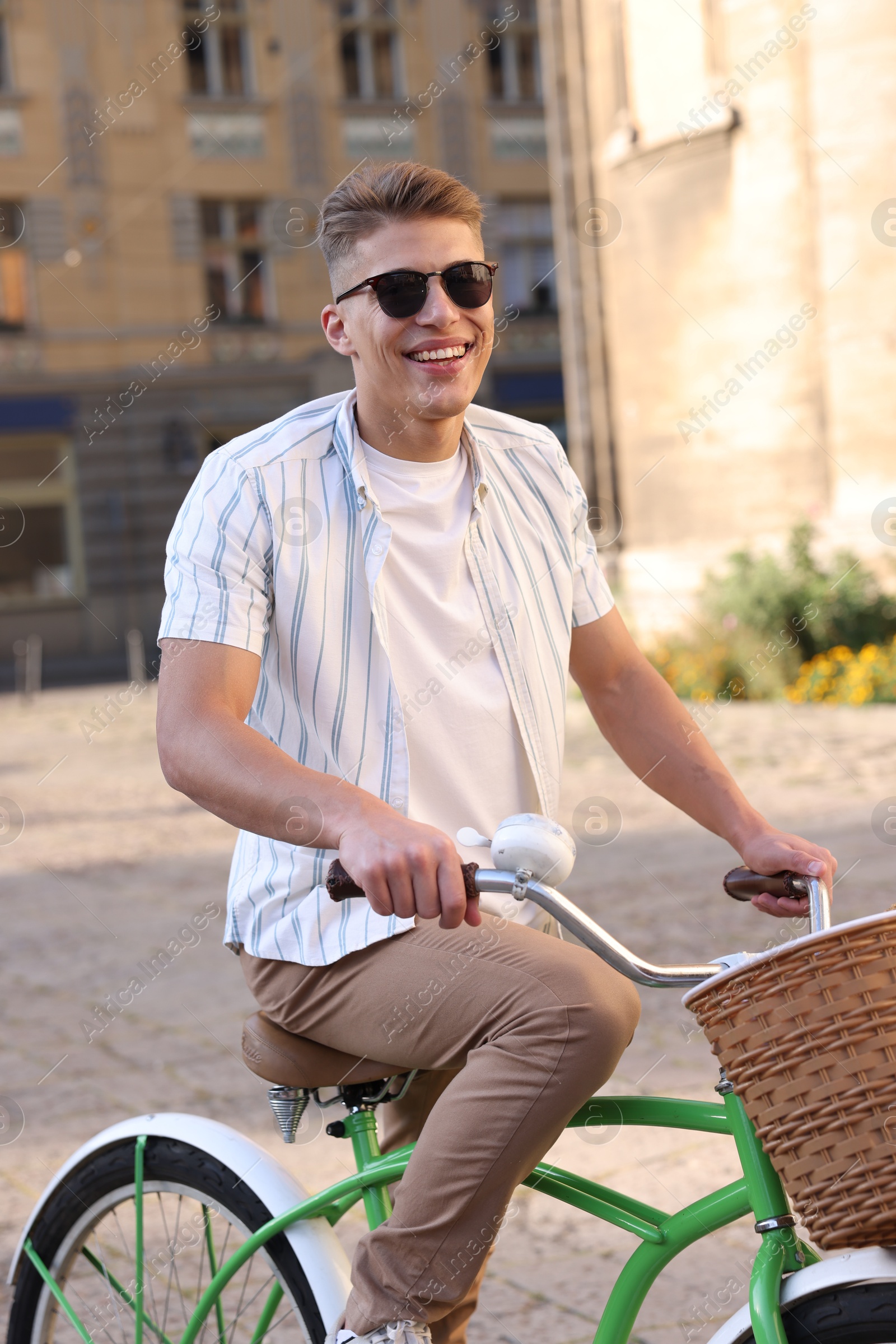 Photo of Happy man in sunglasses riding bicycle on city street