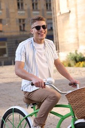 Photo of Happy man in sunglasses riding bicycle on city street