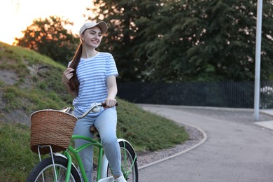 Photo of Happy woman riding bicycle on city street. Space for text
