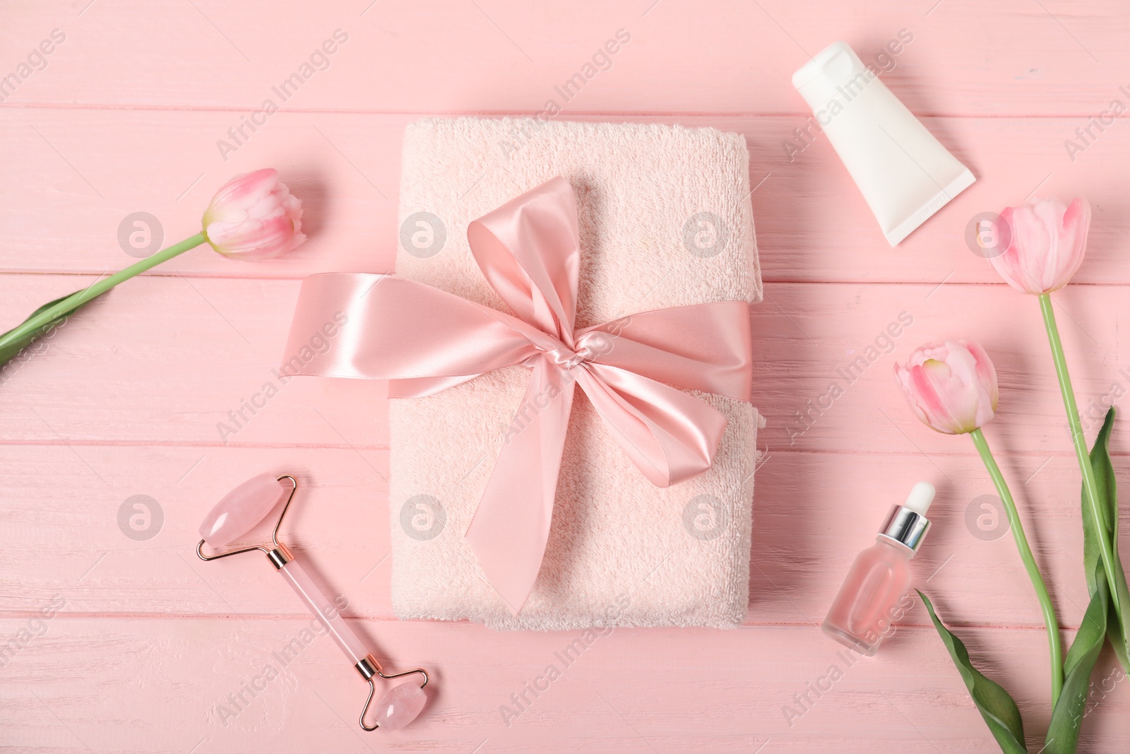 Photo of Fresh terry towel, hygiene products and tulips on pink wooden background, flat lay