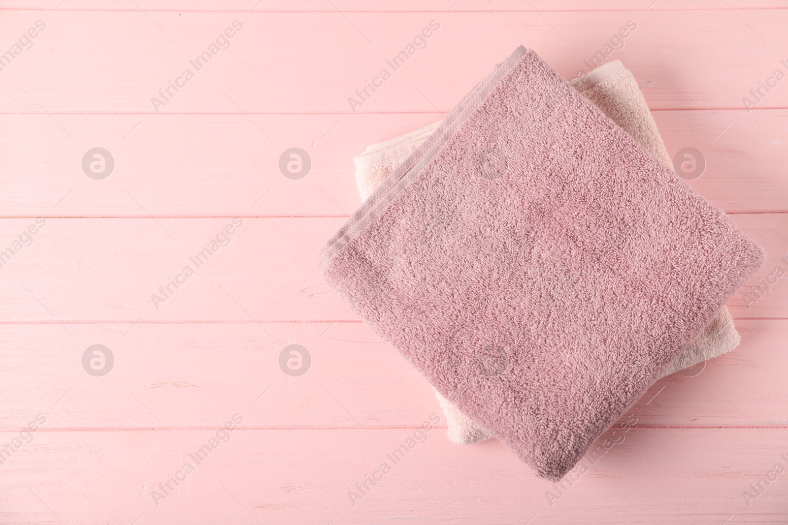 Photo of Fresh terry towels on pink wooden background, top view. Space for text