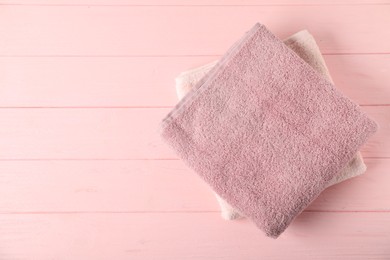 Photo of Fresh terry towels on pink wooden background, top view. Space for text