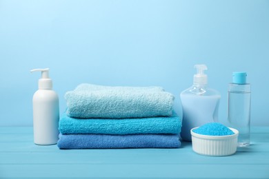 Photo of Fresh terry towels and personal hygiene products on light blue background. Space for text