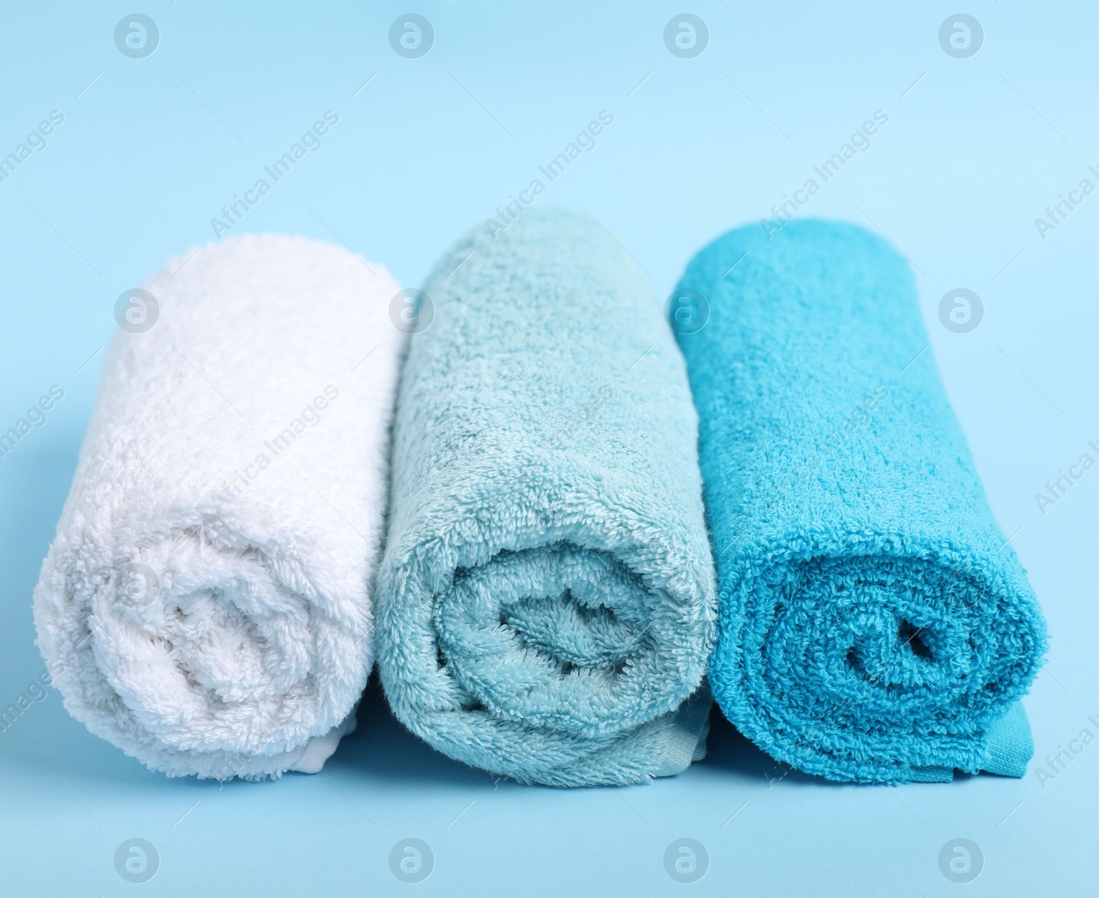 Photo of Fresh terry towels on light blue background