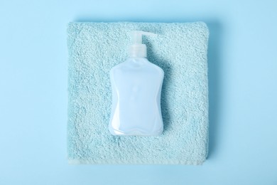 Photo of Fresh terry towel and soap on light blue background, top view
