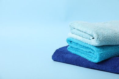 Photo of Stack of fresh terry towels on light blue background. Space for text