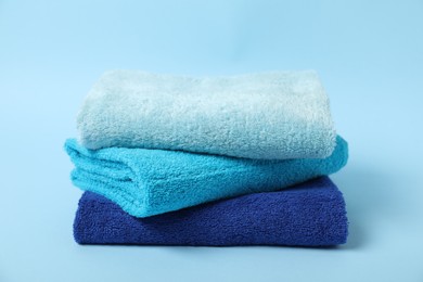 Photo of Stack of fresh terry towels on light blue background