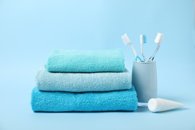 Photo of Fresh terry towels and personal hygiene products on light blue background