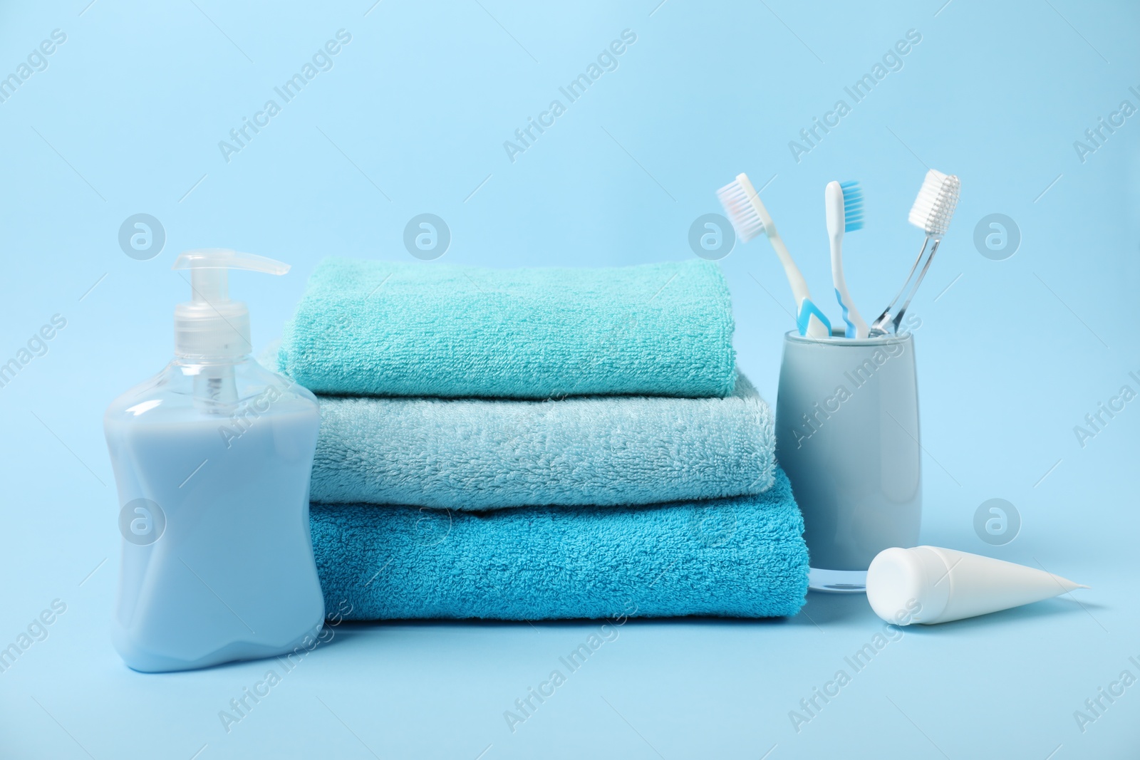 Photo of Fresh terry towels and personal hygiene products on light blue background
