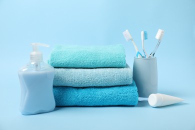 Photo of Fresh terry towels and personal hygiene products on light blue background