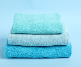 Photo of Stack of fresh terry towels on light blue background