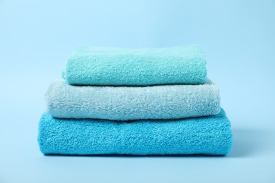 Photo of Stack of fresh terry towels on light blue background
