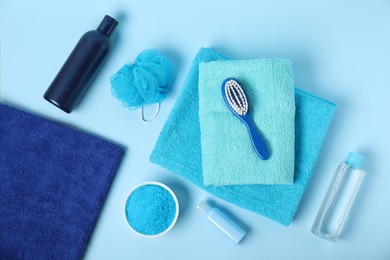 Photo of Fresh terry towels and personal hygiene products on light blue background, flat lay