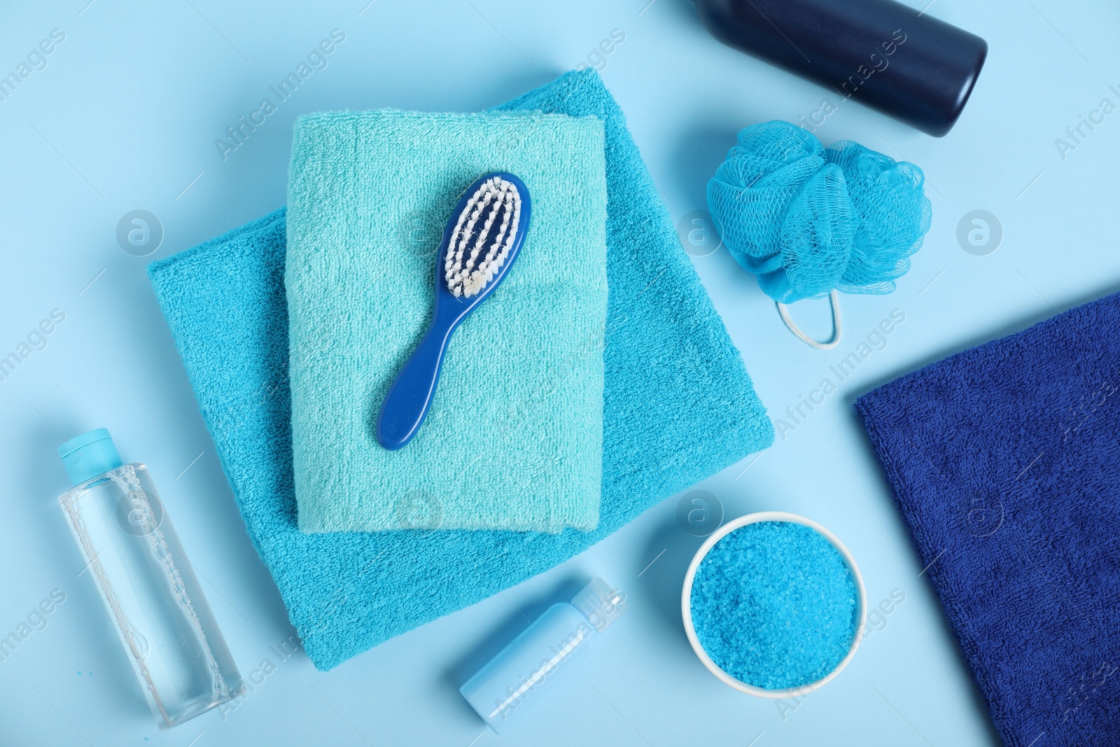 Photo of Fresh terry towels and personal hygiene products on light blue background, flat lay