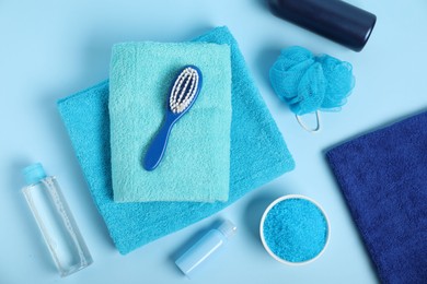 Photo of Fresh terry towels and personal hygiene products on light blue background, flat lay