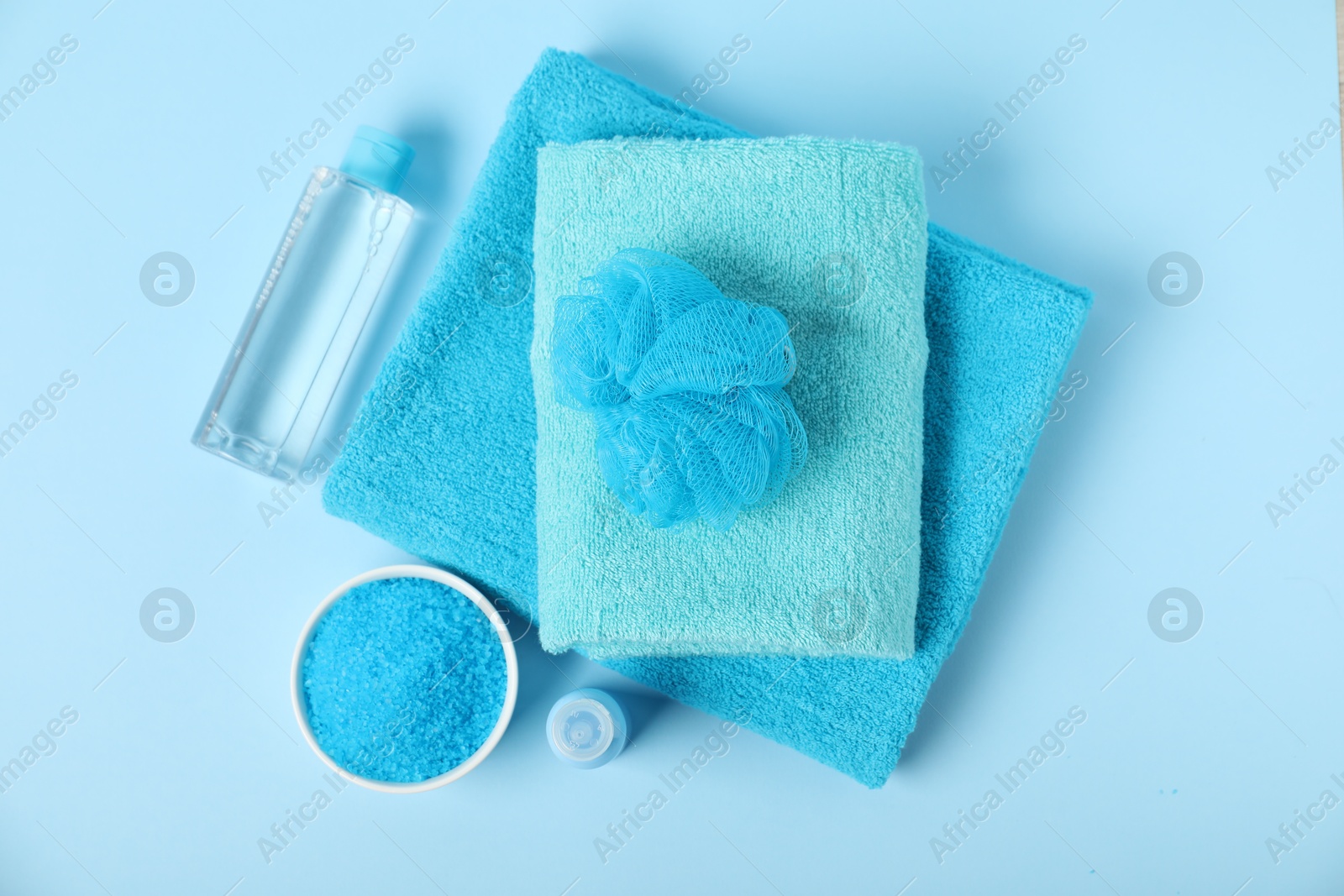 Photo of Fresh terry towels and personal hygiene products on light blue background, flat lay
