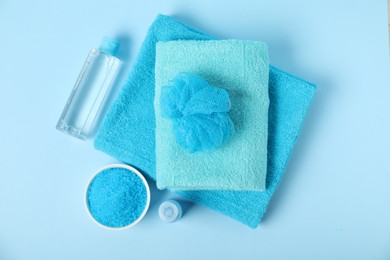 Photo of Fresh terry towels and personal hygiene products on light blue background, flat lay