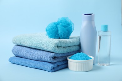 Photo of Fresh terry towels and personal hygiene products on light blue background