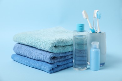 Photo of Fresh terry towels and personal hygiene products on light blue background
