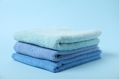 Photo of Stack of fresh terry towels on light blue background