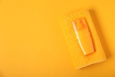 Photo of Fresh terry towel and sunscreen on yellow background, top view. Space for text