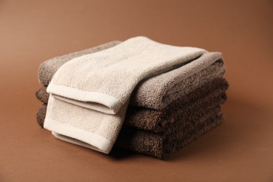 Photo of Stack of fresh terry towels on brown background