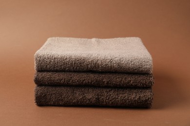 Photo of Stack of fresh terry towels on brown background