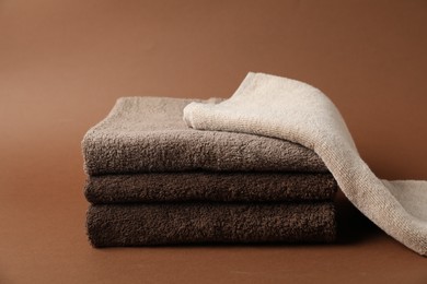 Photo of Stack of fresh terry towels on brown background