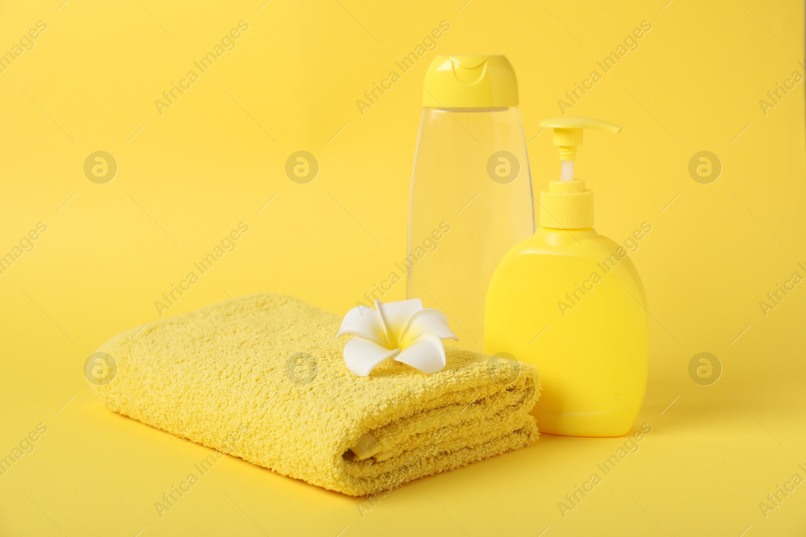 Photo of Fresh terry towel, cosmetic products and flower on yellow background. Space for text